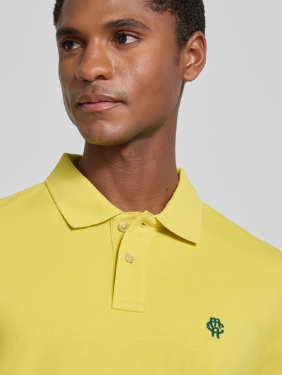 Mężczyznę model nosi Regular Fit Poloshirt mit Label-Stitching von MCNEAL z bawełny, krój regular fit, listwa guzikowa, długość tyłu 70 cm, zbliżenie na górną część ciała
