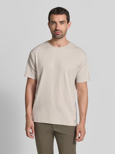 Männermodel trägt T-Shirt mit Rundhalsausschnitt und Rollsaum von Scotch & Soda aus reiner Baumwolle, Relaxed Fit, Beige, Ganzkörperansicht von vorne