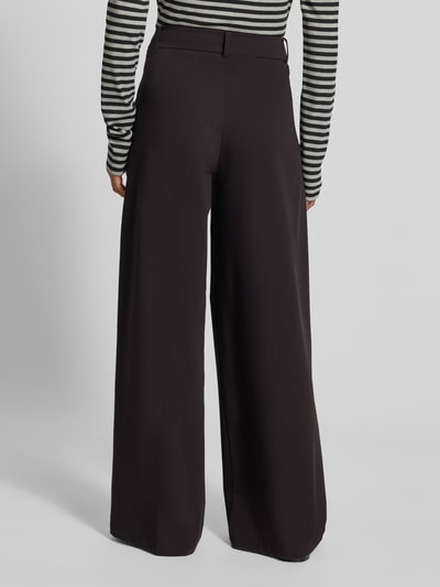 Frauenmodel trägt Wide Fit Hose mit Viskose-Anteil von MYON, dunkel, glatte Oberfläche, Bundfalten, Ganzkörperansicht Rückansicht.
