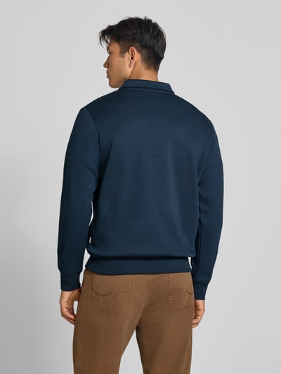 Męski model nosi Regular Fit Sweatshirt mit Baumwoll-Anteil Modell 'Bradley' von JACK & JONES, ciemnoniebieska bluza, mieszanka bawełny, kołnierz zapinany, zamek błyskawiczny, długość tyłu w rozmiarze M 69 cm, widok całej sylwetki od tyłu.