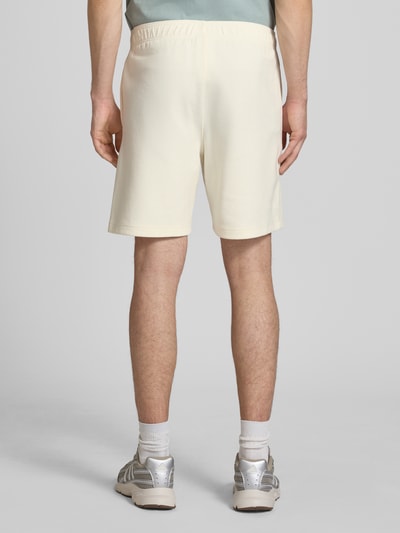 Mężczyzna nosi Shorts mit Label-Stitching mit elastischem Bund od CHAMPION, kolor kremowy, bawełniany miks, krój regular fit, szerokość w rozmiarze M: 37 cm, długość nogawki wewnętrznej: 42 cm, widok całej sylwetki od tyłu