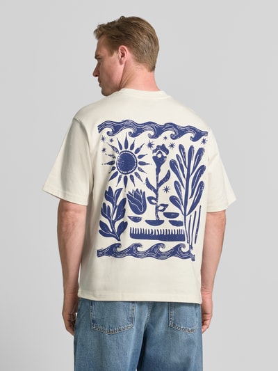 Mężczyznę model nosi T-Shirt mit rückseitigem Motiv-Print von Jake*s z bawełny, krój regular fit, nadruk z motywem i haft z tyłu, okrągły dekolt, długość tyłu w rozmiarze M: 68 cm, kolor kremowy z niebieskim, Ganzkörperansicht Rückansicht.
