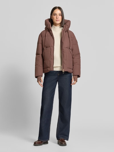 Kobieta modelka nosi Regular Fit kurtkę z efektem pikowania Model 'Ollie' od MOS MOSH, brąz, Kaptur z tunelem, Ganzkörperansicht von vorne. Długość tyłu w rozmiarze S: 65 cm, szerokość ramion w rozmiarze S: 52 cm, szerokość klatki piersiowej w rozmiarze S: 63 cm, długość rękawów w rozmiarze S: 68 cm.