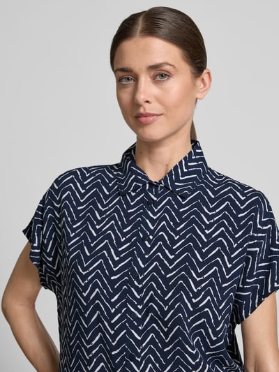 Vrouwenmodel draagt Relaxed Fit Bluse uit viscose in all-over look van Christian Berg Woman, donkerblauw met witte zigzag, overhemdkraag, zuiver viscose, ruglengte maat 36: 63 cm, detailopname bovenlichaam.