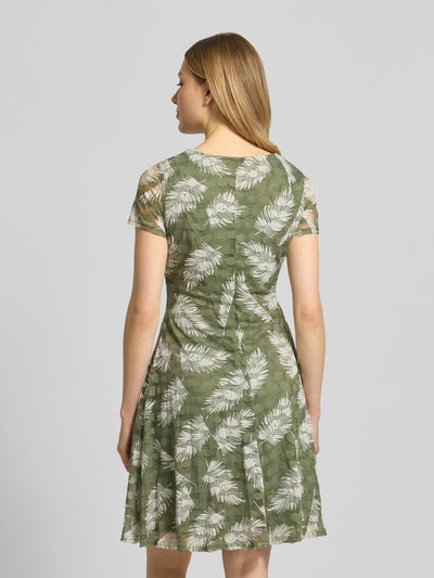 Frauenmodel trägt Knielanges Kleid mit Rundhalsausschnitt von Apricot in Olivgrün mit weißem Blattmuster, A-Linie, Material-Mix mit Stretch-Anteil, blickdichtes Unterkleid, Rückenlänge 93 cm, Brustweite 41 cm, Ärmellänge 17 cm, Ganzkörperansicht Rückansicht.