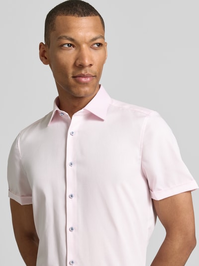 Mężczyzna nosi Slim Fit Business-Hemd mit Kentkragen von OLYMP Level Five, różowa bawełna, krój slim fit, guzik, rękaw z mankietem, długość tyłu w rozmiarze 40 to 70 cm, szerokość ramion w rozmiarze 40 to 40 cm, długość rękawa w rozmiarze 40 to 24 cm, zbliżenie na górną część ciała z przodu.