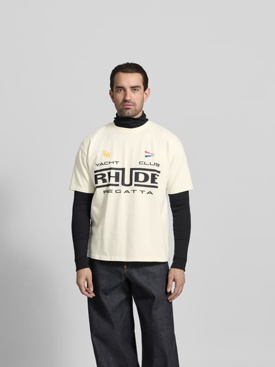 Männermodel trägt Relaxed Fit T-Shirt mit Logo-Print von RHUDE, Herren T-Shirt aus reiner Baumwolle, Rundhalsausschnitt, Kurzärmelig, Rückenlänge 68 cm, Ganzkörperansicht von vorne.