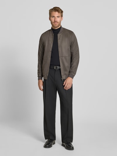 Męski model nosi Regular Fit Bomberjacke mit Stehkragen von Christian Berg Men z elastycznej mieszanki materiałów, wpuszczane kieszenie, zamek błyskawiczny, długość tyłu w rozmiarze M: 60 cm, długość rękawów w rozmiarze M: 67 cm, stonowane kolory, gładka faktura, widok całej sylwetki z przodu.