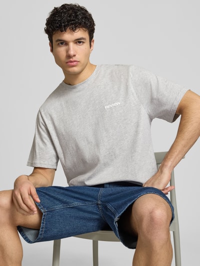 Männermodel trägt T-Shirt mit Logo und Rundhalsausschnitt von REVIEW in Grau, Baumwoll-Viskose-Mix, Regular-Fit, Ganzkörperansicht von vorne. Rückenlänge bei Größe M: 64 cm.