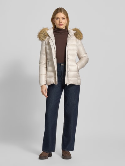 Modelka nosi Daunenjacke mit Kapuze Modell 'Alma' od ROCK'N BLUE, krój slim fit, kremowy połysk, kaptur ze sztucznym futrem, zamek, listwa na guziki, kieszenie na zamek, wypełnienie z puchu i pierza, długość pleców w rozmiarze 36: 66 cm, szerokość ramion w rozmiarze 36: 36 cm, szerokość w biuście w rozmiarze 36: 45 cm, długość rękawa w rozmiarze 36: 60 cm, produkt wypada bardzo mały, widok całej sylwetki z przodu.