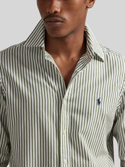 Męskimodel nosi Custom Fit Freizeithemd aus reiner Baumwolle von Polo Ralph Lauren, efekt: wzór na całej powierzchni, krój custom fit, kołnierzyk typu kent, jednorzędowa listwa guzikowa, wzór w paski, wyhaftowane logo, zapięcie na guziki, długi rękaw, mankiet, lekko zaokrąglone wykończenie, bawełna; zbliżenie na górną część ciała