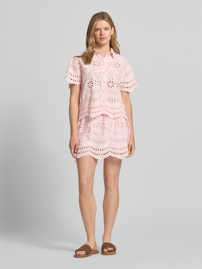 Frauenmodel trägt Mini-Skort aus reiner Baumwolle Modell 'NALA-LALISA' von Only in Optik: Unifarben mit Lochstickmuster, Muschelsaum, leicht ausgestellte Passform, Mini-Länge, Bundabschluss: elastisch, Materialverarbeitung: Lochstick, zartrosa Farbton, strukturierte Oberfläche, Ganzkörperansicht von vorne.