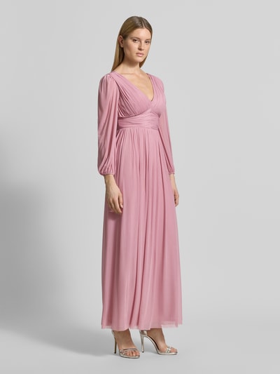 Vrouwenmodel draagt Regular Fit avondjurk in plooien-look van Lipsy in roze met V-hals, elastische materiaalmix, met lange mouwen, getailleerd, onderrok, ruglengte maat 36: 135 cm, borstwijdte: 45 cm, mouwlengte: 62 cm, volledige lichaamsaanzicht vooraan.