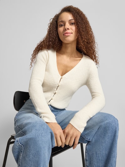 Frauenmodel trägt Regular Fit Strickjacke mit Perl-Optik-Knöpfen Modell 'RICA LIFE' von ONLY, Optik: Unifarben, V-Ausschnitt, Langarm, Rippstrick-Material, einreihige Knopfleiste, Ganzkörperansicht von vorne.