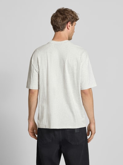 Männermodel trägt Oversized T-Shirt mit Label-Stitching von Pegador aus Baumwoll-Mix in Hellgrau, Rückenlänge 70 cm, Ganzkörperansicht Rückansicht.
