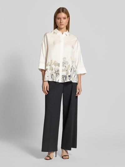 Frauenmodel trägt Relaxed Fit Hemdbluse aus reiner Seide mit Floralem-Print von HERZENS, Hemdblusenkragen, 3/4-Arm, durchgängige Knopfleiste. Rückenlänge 73 cm, Ärmellänge 43 cm, ganzkörperansicht von vorne.