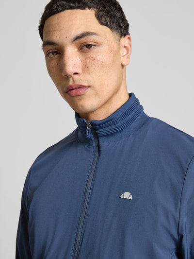 Männermodel trägt Sweatjacke mit Logo-Print Modell 'CANDORA' von Ellesse in Dunkelblau, Reißverschluss, Stehkragen, Nahaufnahme Oberkörper