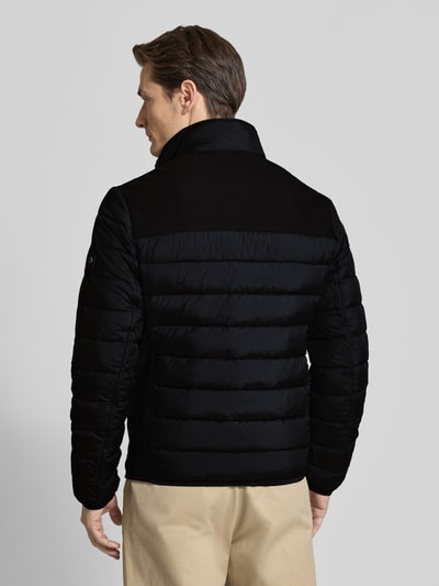 Männermodel trägt Regular Fit Steppjacke mit seitlichen Stretcheinsätzen von Tom Tailor, Optik: Unifarben, Ganzkörperansicht Rückansicht.