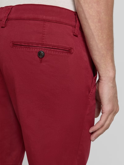 Männermodel trägt Hose mit Gesäßtaschen von Christian Berg Men aus Baumwoll-Elasthan-Mix, Slim-Fit, kräftiges Rot, Nahaufnahme Rückansicht.