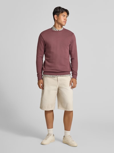 Männermodel trägt Regular Fit Sweatshirt aus Baumwoll-Mix Modell 'CERES' von ONLY & SONS, warme Erdtöne, beige Shorts, Ganzkörperansicht von vorne.