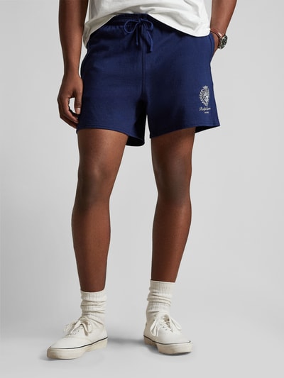 Männermodel trägt Regular Fit Sweatshorts aus reiner Baumwolle von Polo Ralph Lauren in Dunkelblau mit Label Stitching, Nahaufnahme Oberschenkel.