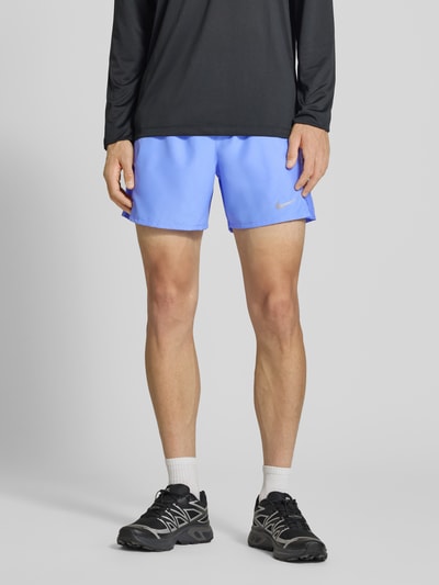 Männermodel trägt Shorts mit seitlichen Eingrifftaschen und Logo-Print von NIKE TRAINING, hellblau, Loose Fit, Ganzkörperansicht von vorne.
