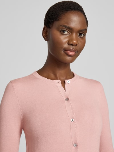 Vrouwenmodel draagt Regular Fit gebreid jack uit Viscosemix met geschulpte zoom, knoopsluiting, ribboorden van Christian Berg Woman, nahaufnahme bovenlichaam.