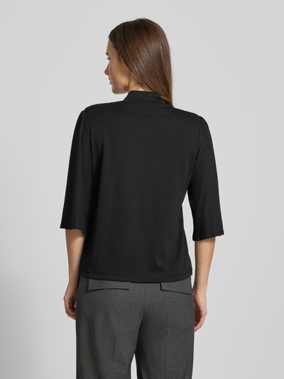 Frauenmodel trägt Longsleeve mit 3/4-Ärmel von Marc Cain, schwarzer Baumwoll-Elasthan-Mix, lockerer Schnitt, Stehkragen, Rückenlänge 57 cm, Ganzkörperansicht Rückansicht.