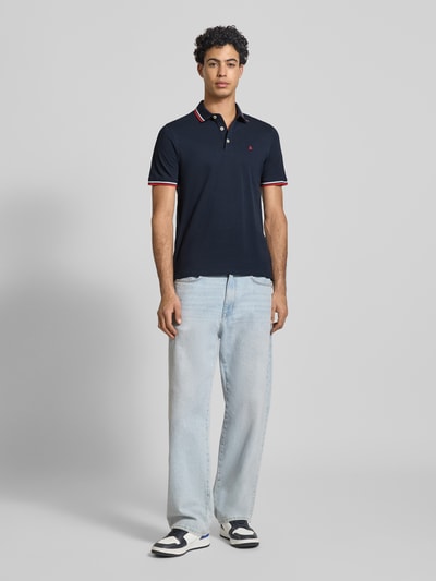 Männermodel trägt Slim Fit Poloshirt mit Viskose-Anteil Modell 'Paulos' von JACK & JONES, Baumwoll-Mix, Polokragen, Logo-Stitching, Ganzkörperansicht von vorne.