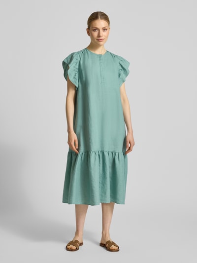 Kobiece model prezentuje Leinenkleid mit Rüschen und Rundhalsausschnitt od Christian Berg Woman, czyste len, krój A-linia, midikleid, okrągły dekolt, falbany, długość tyłu w rozmiarze 36: 118 cm, szerokość w rozmiarze 36: 52 cm, długość rękawa w rozmiarze 36: 15 cm, jasny turkus, luźna faktura, pełny widok z przodu.