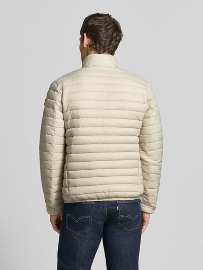 Männermodel trägt Steppjacke mit Zweiwege-Reißverschluss Modell 'ALEXANDER' von Save The Duck, beige, Rückenansicht, strukturierte Oberfläche, Kontext: Herren Steppjacke, Slim Fit, Stehkragen, Reißverschlusstaschen, Maße Größe M