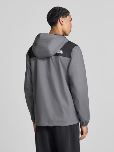 Männermodel trägt Jacke mit Label-Print Modell 'ANTORA' von The North Face in Grau mit schwarzem Schulterbereich, Ganzkörperansicht Rückansicht. Rückenlänge 74 cm, gerade Passform, Kapuze mit Tunnelzug, Reißverschlusstaschen, elastische Ärmelabschlüsse.