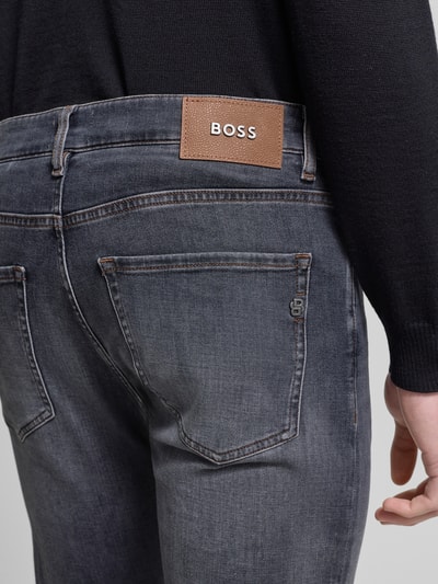 Männermodel trägt Slim Fit Jeans aus Baumwoll-Mix Modell 'DELAWARE' von BOSS, Denim-Optik, Label-Patch, 5-Pocket-Design, Detailaufnahme