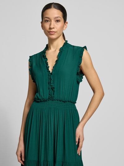 Frauenmodel trägt Maxikleid aus Viskose mit V-Ausschnitt und Rüschen von Apricot in sattem Grün, A-Linie, Stufen-Look, Nahaufnahme Oberkörper. Rückenlänge bei Größe S: 139 cm, Brustweite bei Größe S: 34 cm.