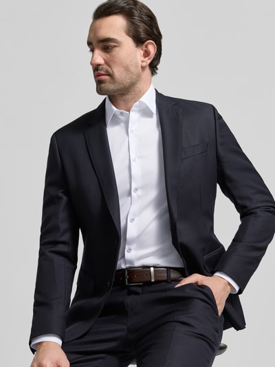 Męski model nosi Slim Fit Businesshemd mit Kentkragen od OLYMP No. Six, elastyczna mieszanka bawełny, krój slim fit, kołnierzyk kent, pełna lista guzików, długi rękaw, mankiety sportowe, długość pleców w rozmiarze 40: 81 cm, szerokość ramion w rozmiarze 40: 43 cm, długość rękawa w rozmiarze 40: 67 cm, kolor biały, gładka tekstura, widok całej sylwetki z przodu.