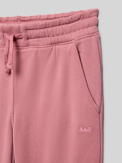Productfoto, wide fit sweatpants van katoenmix model 'ESSENTIAL' van Abercrombie&Fitch, roze, tunnelkoord, zijzakken, geborduurd label, binnenbeenlengte maat 134: 60 cm