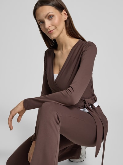 Kobiece modelka ma na sobie Cropped Wickelshirt mit V-Ausschnitt von aim'n, mieszanka materiałów z dodatkiem streczu, krój krótki, bluzka z długim rękawem, dekolt w serek, długość tyłu w rozmiarze S: 40 cm, zdjęcie w ujęciu z przodu, detal górnej części ciała.