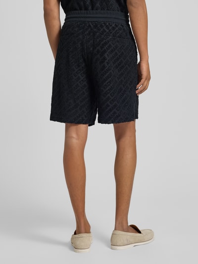 Männermodel trägt Shorts mit Logo-Muster und elastischem Bund van ARMANI EXCHANGE, zwart katoen-elastaanmix, regular fit, elastische tailleband, logo allover, detailopname achterkant.