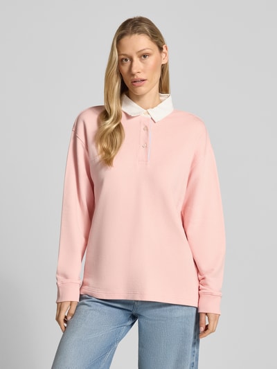 Frauenmodel trägt Longsleeve mit Polokragen und kurzer Knopfleiste von Gant, rosa Baumwoll-Mix, Loose Fit, Ganzkörperansicht von vorne.