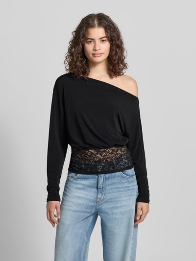 Vrouwenmodel draagt shirt met lange mouwen met asymmetrische hals, kant, nauwsluitend model, model 'Mirelin' van Gina Tricot, materiaalmix met stretch, ruglengte bij maat S 52 cm, voorkant volledige lichaamsopname.