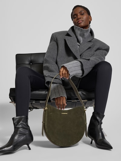 Frauenmodel trägt Shoulder Bag mit Logo-Detail von Victoria Beckham in Olivgrün-Suede mit Magnetverschluss, schmalem Schulterriemen und offenem Hauptfach, Ganzkörperansicht von vorne.