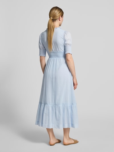 Frauenmodel trägt Damen Midikleid mit V-Ausschnitt, Rüschen und Häkelspitze Modell 'Alvina' von Neo Noir aus reiner Baumwolle, Taillierter Schnitt, Farbton Hellblau, Rückenlänge 117 cm, Brustweite 43 cm, Ärmellänge 34 cm, Ganzkörperansicht Rückansicht.