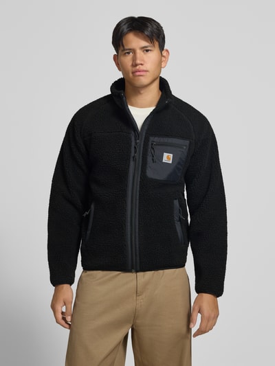 Männermodel trägt Teddyjacke mit Brusttasche Modell 'PRENTIS LINER' von Carhartt Work In Progress in Schwarz, Reißverschluss, Label-Patch, Ganzkörperansicht von vorne, Herrenjacke Regular Fit.