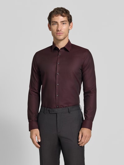 Männermodel trägt Super Slim Fit Businesshemd aus Baumwoll-Mix von OLYMP No. Six in Dunkelrot, glatte Textur, Ganzkörperansicht von vorne.