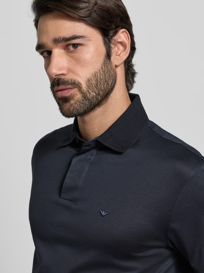 Männermodel trägt Poloshirt mit kurzer Knopfleiste von Emporio Armani, Lyocell-Baumwolle-Mix, Regular Fit, Label-Stitching, Nahaufnahme Oberkörper.