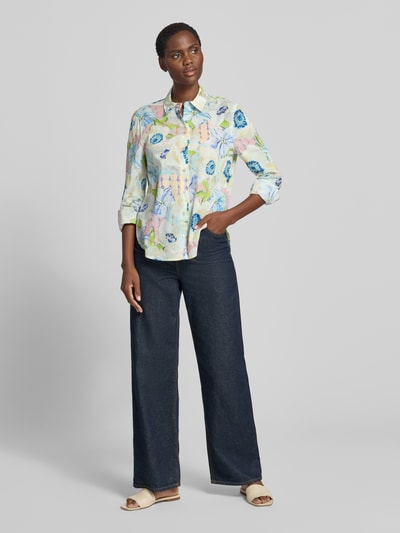 Modelka kobieca nosi Regular Fit Hemdbluse mit floralem Allover-Print von Christian Berg Woman z bawełny, długie rękawy, całkowity nadruk kwiatowy, kołnierzyk koszulowy, tylna część wydłużona, długość tyłu w rozmiarze 36: 69 cm, długość rękawa: 62 cm, widok całej sylwetki z przodu.