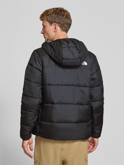 Männermodel trägt Regular Fit Jacke in Stepp-Optik von The North Face in Schwarz mit Kapuze, Logo-Print, Ganzkörperansicht Rückansicht.