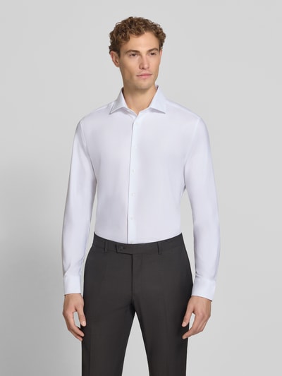 Männermodel trägt weißes Slim Fit Business Hemd mit Kentkragen aus Feintwill von Seidensticker, glatter Baumwoll-Mix, Ganzkörperansicht von vorne.