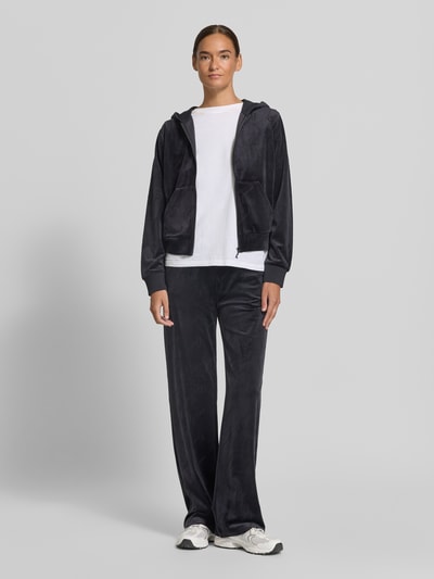 Frauenmodel trägt Sweatjacke mit Logo-Muster Modell 'LOREN' von GUESS, dunkler Farbton, weiche Textur, Ganzkörperansicht von vorne.