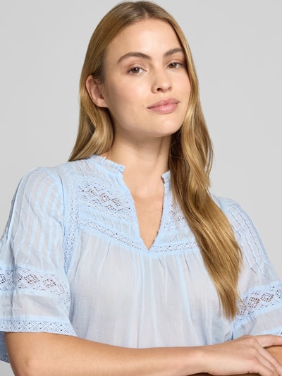 Frauenmodel trägt Damen Bluse mit Häkelspitze Modell 'Siama' von Neo Noir in Hellblau, Serafino-Kragen, 1/2-Arm, Nahaufnahme Oberkörper. Rückenlänge bei Größe 36: 58 cm, Ärmellänge: 30 cm. Loose-Fit, feine Struktur und luftiger Stoff.